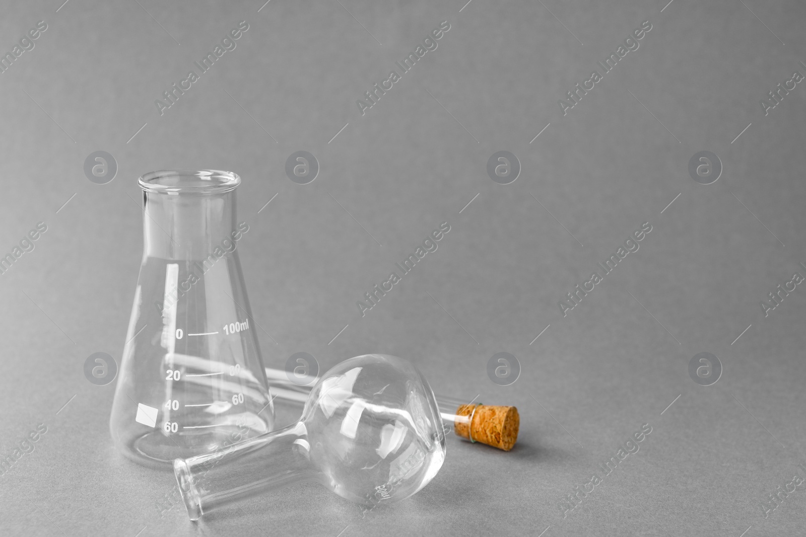 Photo of Different laboratory glassware on grey background, space for text