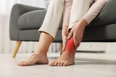 Woman suffering from pain in ankle indoors, closeup