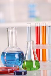 Laboratory analysis. Glass flasks, Petri dish and test tubes with liquids on white table against blurred background