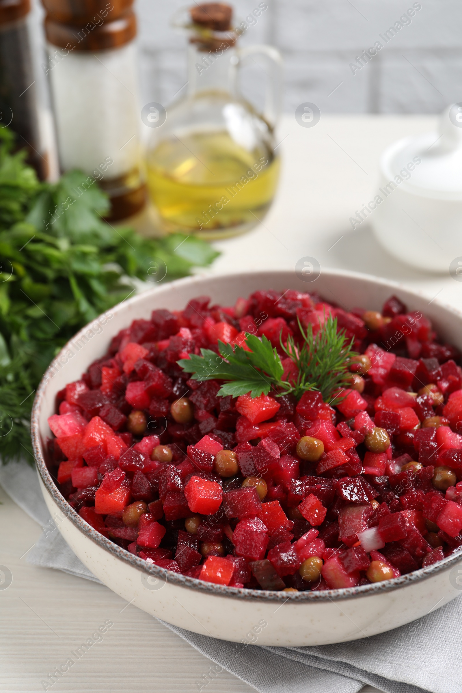 Photo of Bowl of delicious fresh vinaigrette salad on white wooden table, closeup