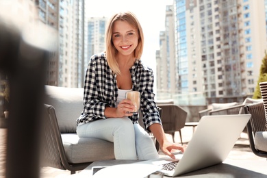 Photo of Beautiful woman with laptop and coffee at outdoor cafe