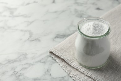 Photo of Baking powder in jar on white marble table, space for text