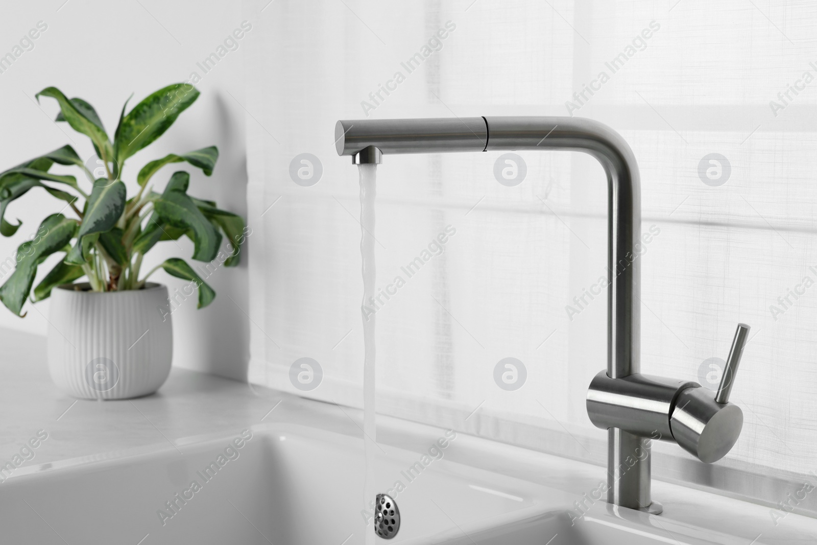 Photo of Stream of water flowing from tap in kitchen