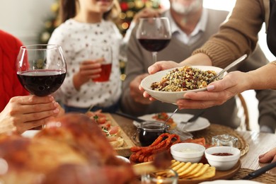 Photo of Woman with bowl of traditional Christmas kutia and her family at festive dinner, closeup. Slavic dish