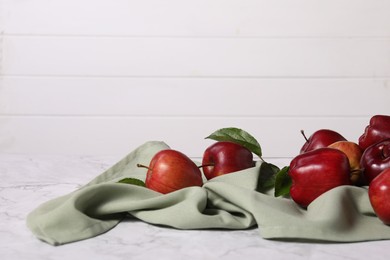 Photo of Fresh ripe red apples with leaves on white marble table. Space for text