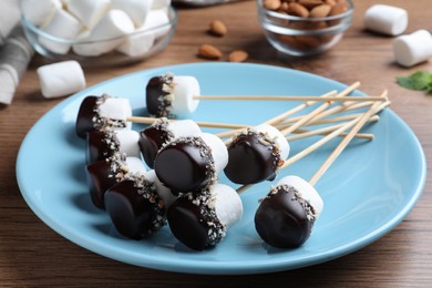 Delicious marshmallows covered with chocolate on wooden table