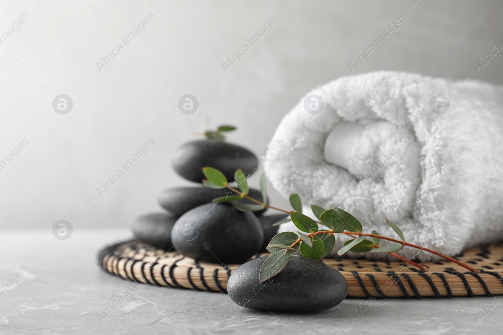 Photo of Composition with spa stones, towel and green leaves on grey table, space for text