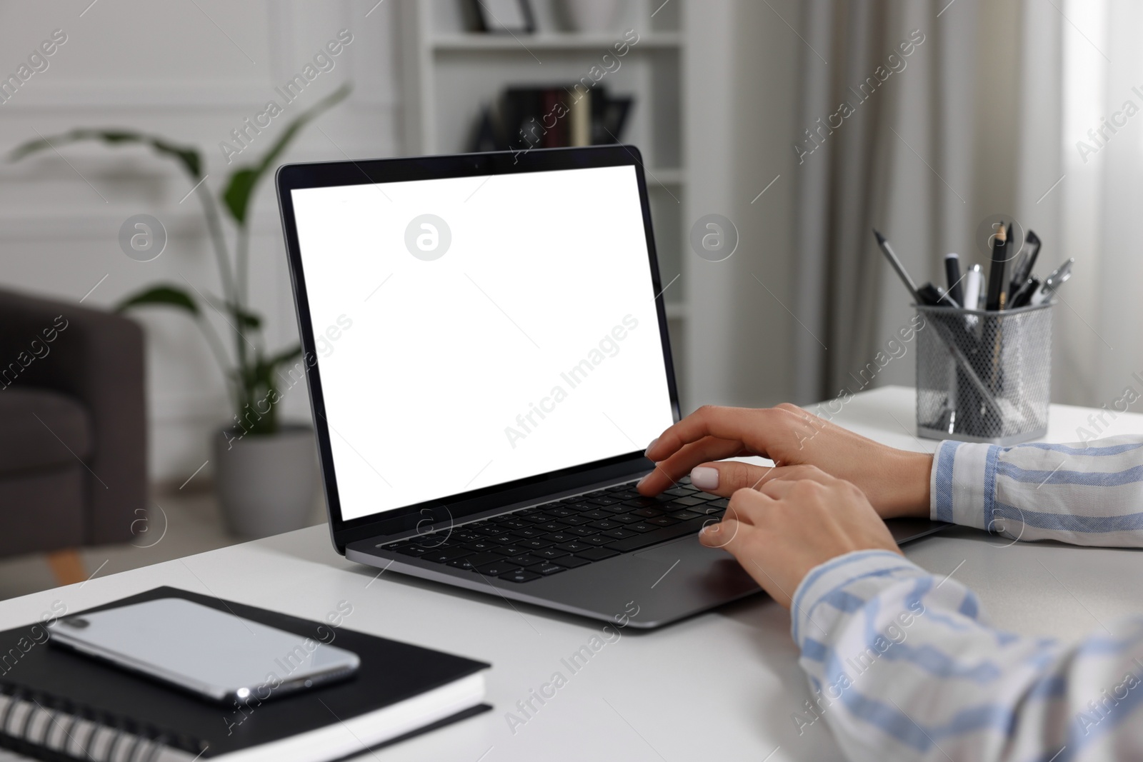 Photo of Woman working with laptop at white desk indoors, closeup