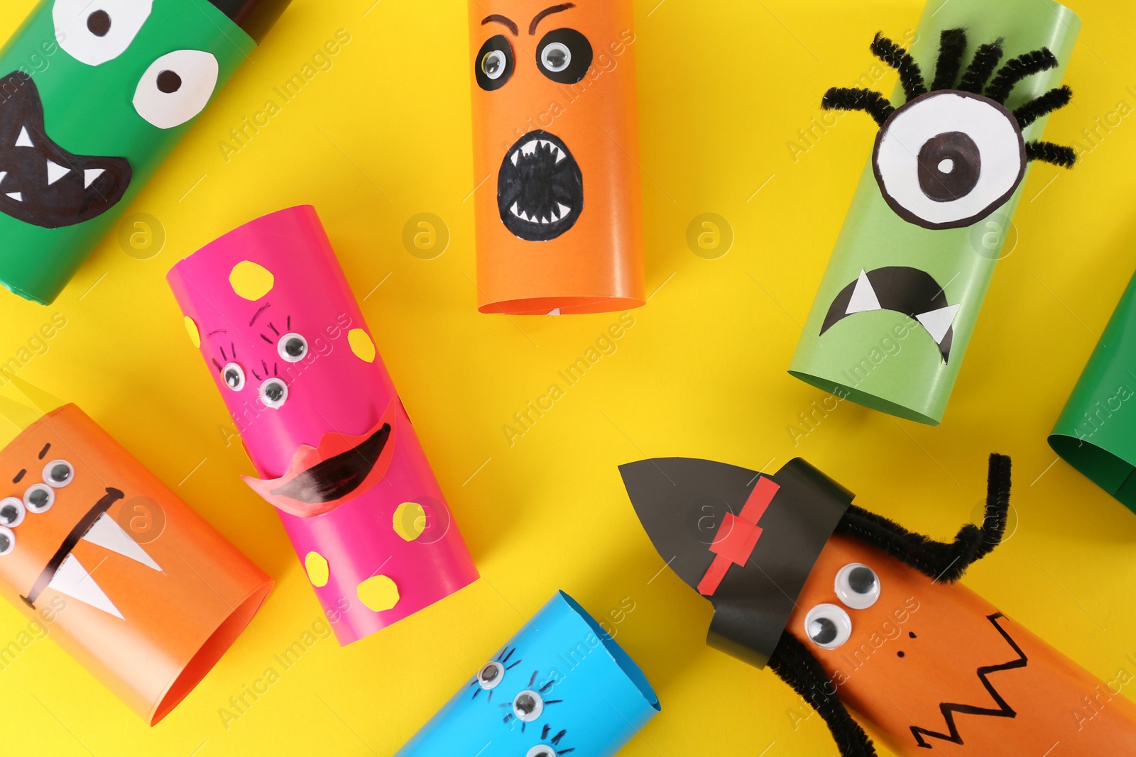 Photo of Funny monsters on yellow background, flat lay. Halloween decoration