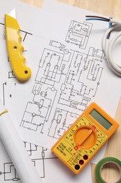 Wiring diagram, wires and digital multimeter on wooden table, closeup