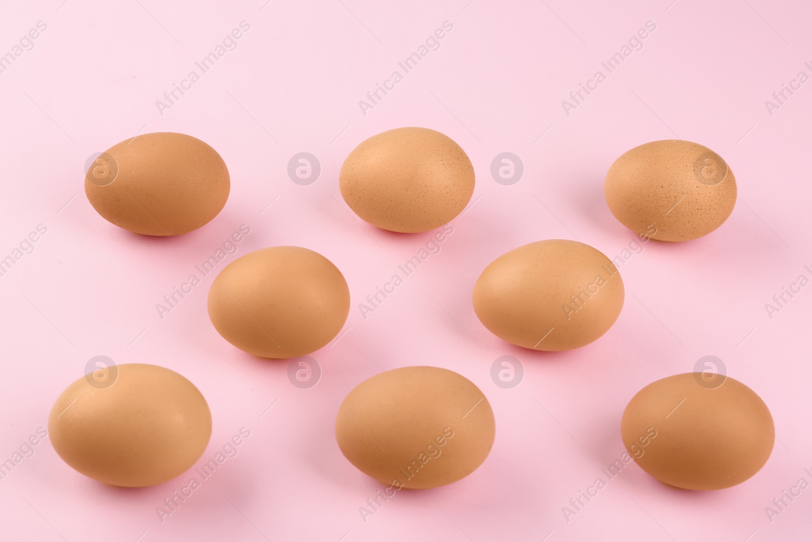 Photo of Raw chicken eggs on pink background, flat lay