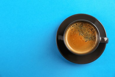 Photo of Cup of tasty coffee on light blue background, top view. Space for text