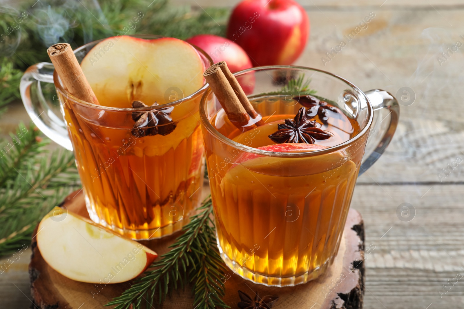 Photo of Hot mulled cider, ingredients and fir branches on wooden table