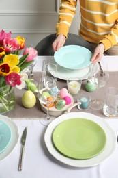 Woman setting table for festive Easter dinner at home, closeup