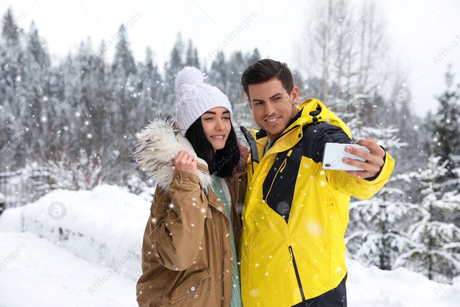 Photo of Happy couple taking selfie near snowy forest. Winter vacation