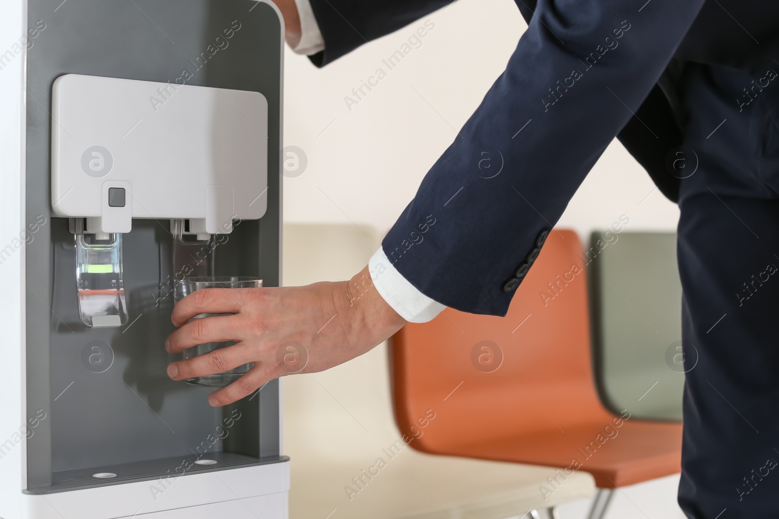 Photo of Man filling glass from water cooler indoors, closeup