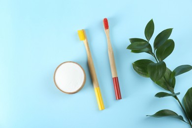 Photo of Bamboo toothbrushes and bowl of baking soda on light blue background, flat lay