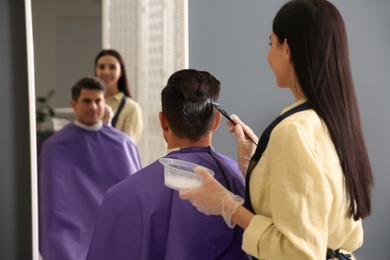 Photo of Professional hairdresser dying hair in beauty salon, back view