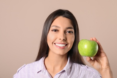 Young woman with healthy teeth and apple on color background