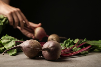Fresh beets with leaves on grey table against black background, closeup. Space for text