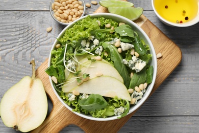 Fresh salad with pear on grey wooden table, flat lay