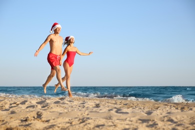 Happy couple with Santa hats together on beach. Christmas vacation