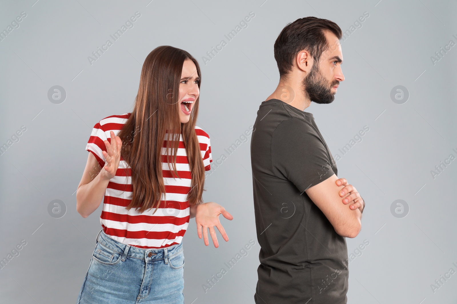 Photo of Woman shouting at her boyfriend on grey background. Relationship problems