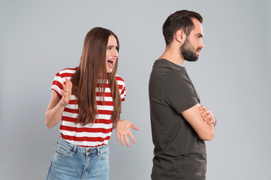 Photo of Woman shouting at her boyfriend on grey background. Relationship problems