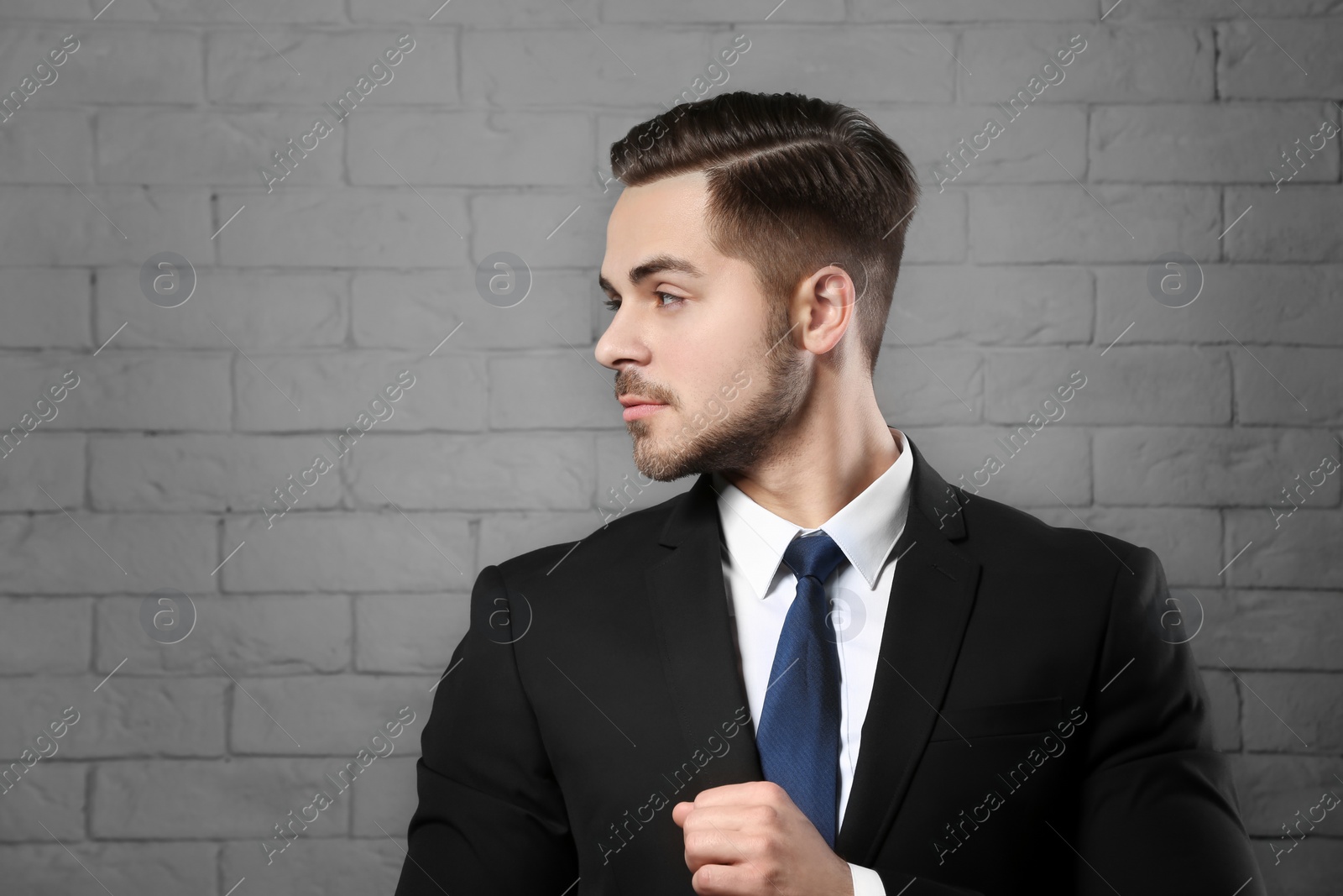 Photo of Portrait of young man with beautiful hair on brick wall background