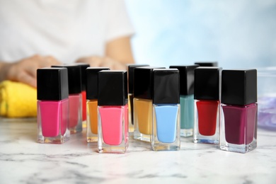 Bottles of bright nail polish and blurred woman on background