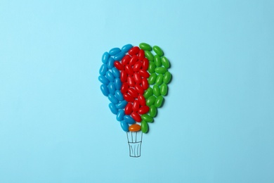 Photo of Bright jelly candies arranged as air balloon on color background, flat lay