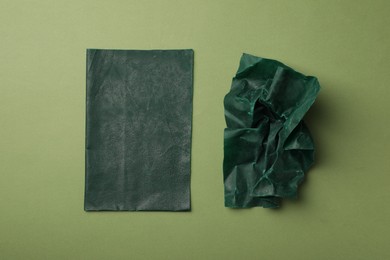 Photo of Reusable beeswax food wraps on green background, flat lay