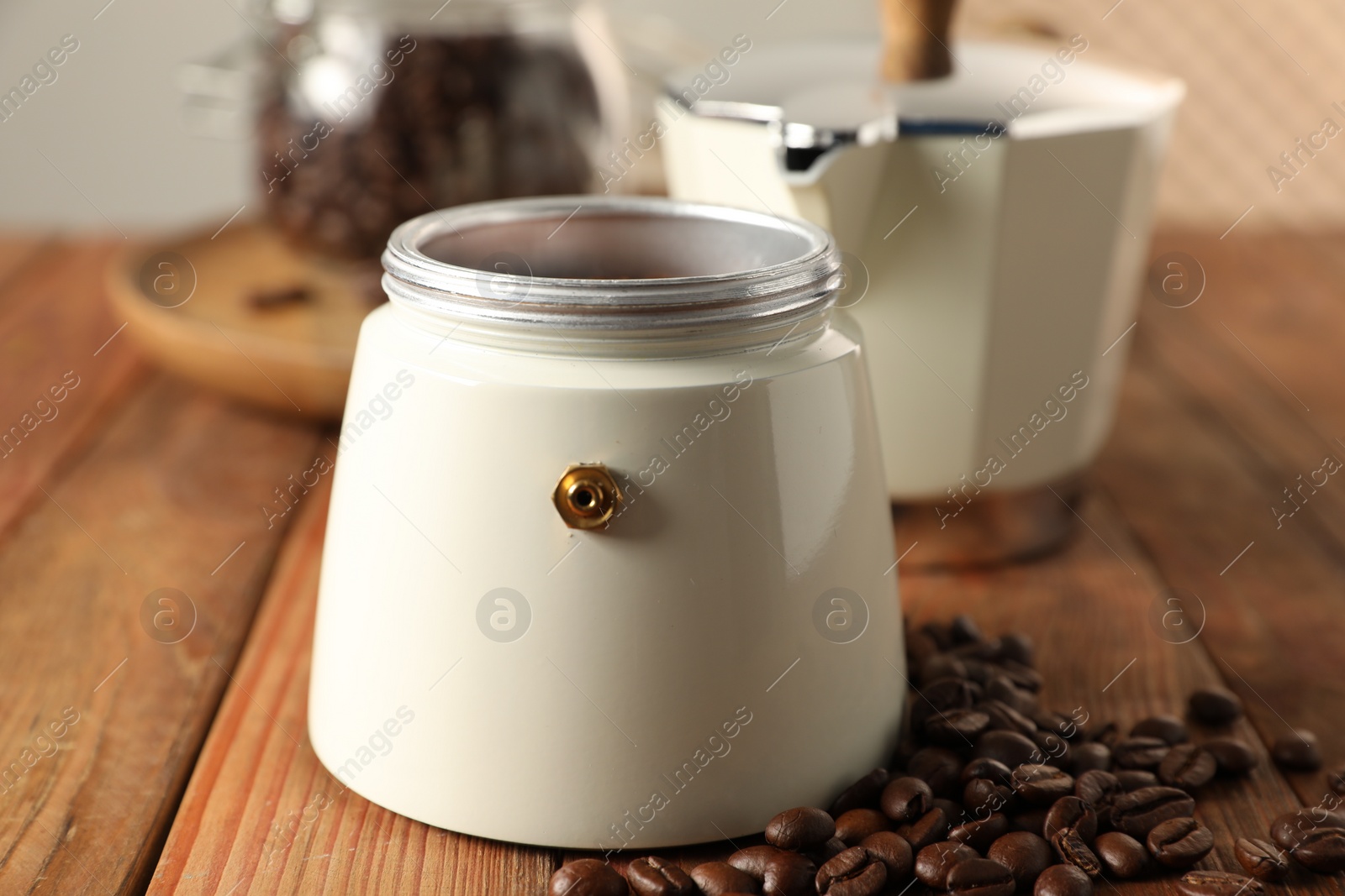 Photo of Moka pot and coffee beans on wooden table, closeup