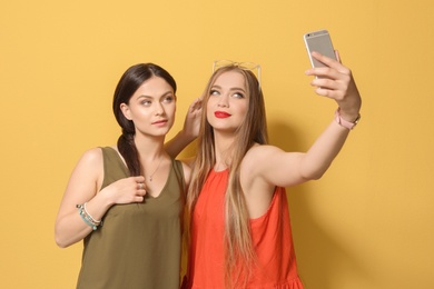 Photo of Attractive young women taking selfie on color background