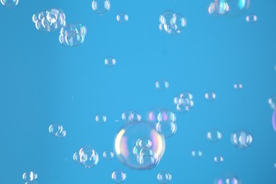 Photo of Beautiful transparent soap bubbles on light blue background