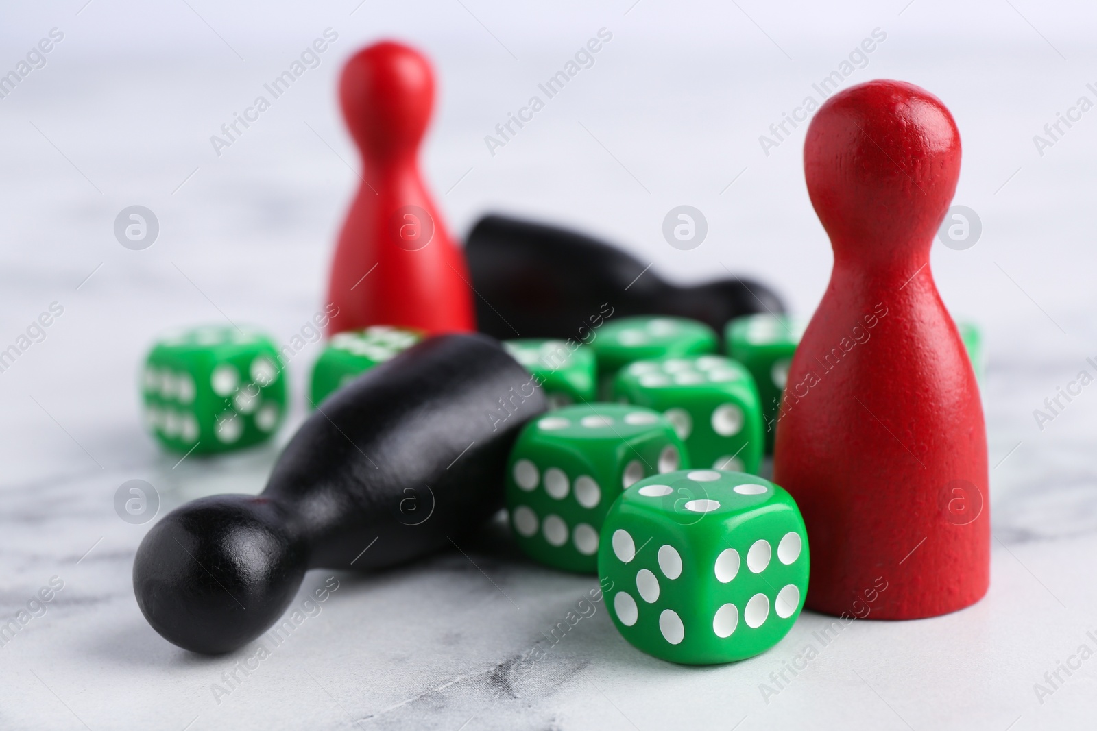 Photo of Green dices and color game pieces on white marble table, closeup