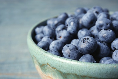 Photo of Crockery with juicy and fresh blueberries on wooden table, closeup