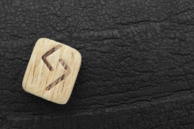 Wooden rune Jera on black textured background, top view. Space for text