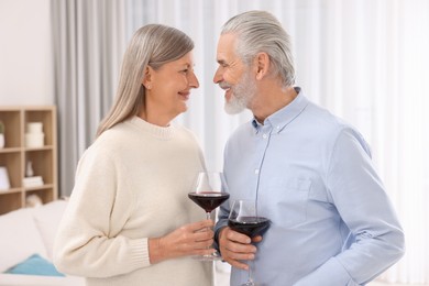 Photo of Affectionate senior couple with glasses of wine indoors