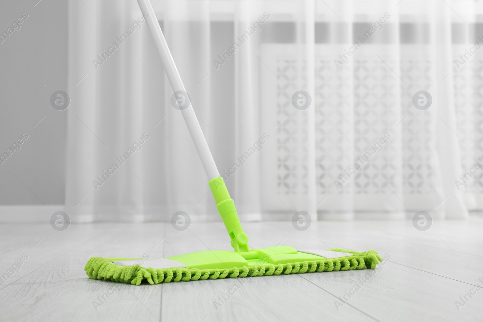 Photo of Cleaning dirty wooden floor with mop indoors