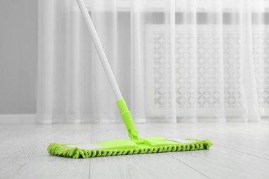 Cleaning dirty wooden floor with mop indoors