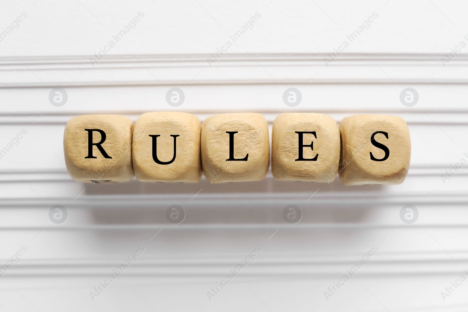 Photo of Word Rules made of wooden cubes with letters on white paper, flat lay