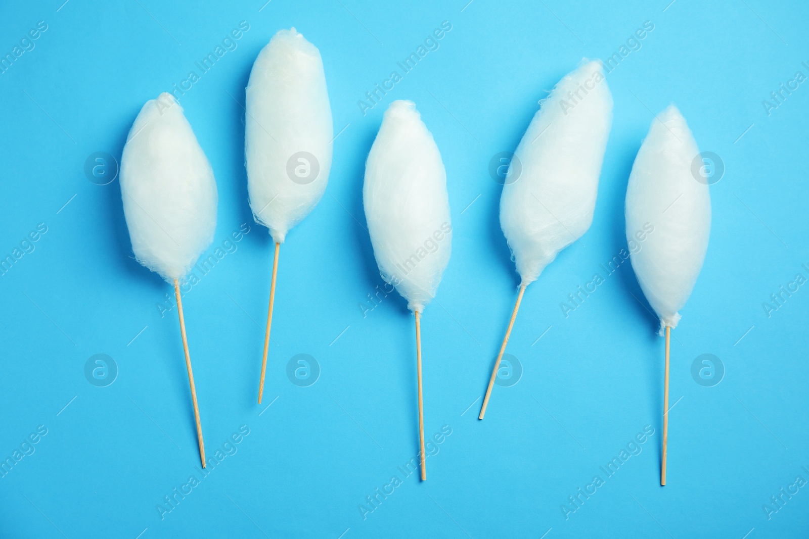 Photo of Sticks with yummy cotton candy on color background, top view