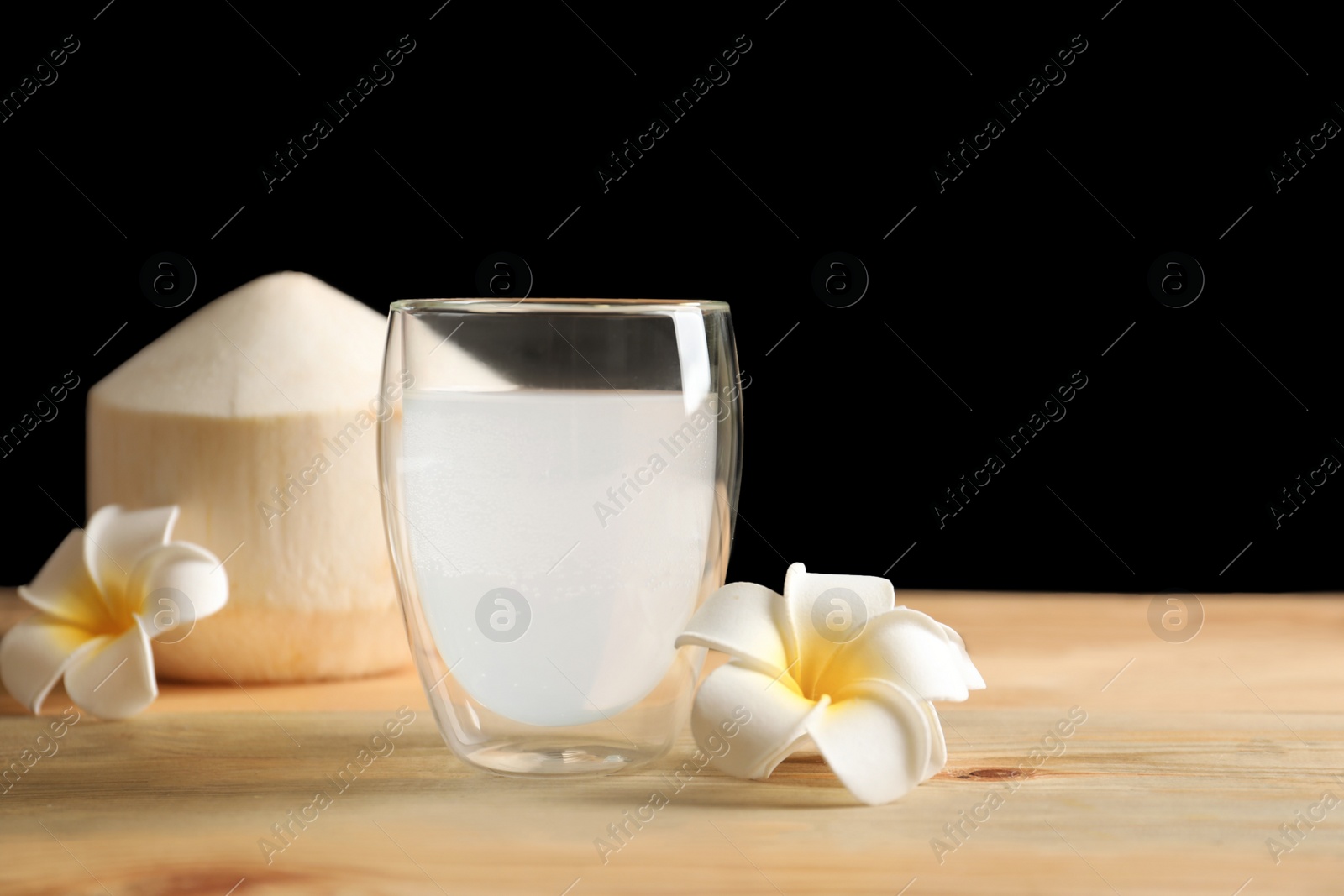 Photo of Glass with fresh coconut water on wooden table