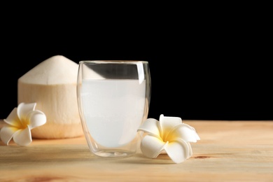 Photo of Glass with fresh coconut water on wooden table