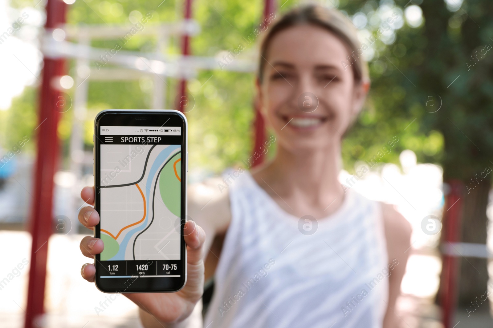 Photo of Young woman showing smartphone with fitness app outdoors, focus on device