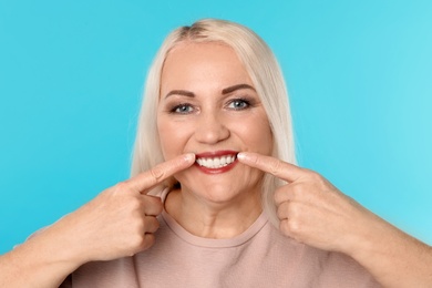Photo of Woman showing perfect teeth on color background