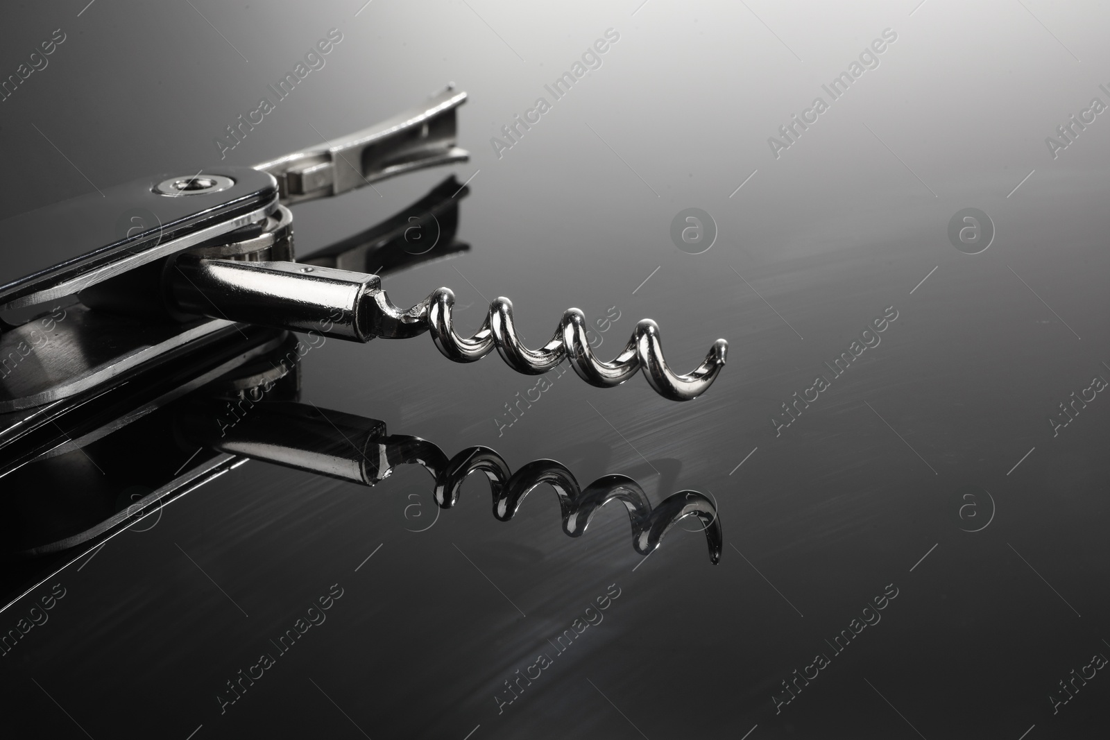 Photo of One corkscrew (sommelier knife) on mirror surface, closeup. Space for text