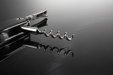 Photo of One corkscrew (sommelier knife) on mirror surface, closeup. Space for text