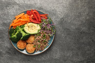 Photo of Delicious vegan bowl with cutlets, buckwheat and broccoli on grey table, top view. Space for text